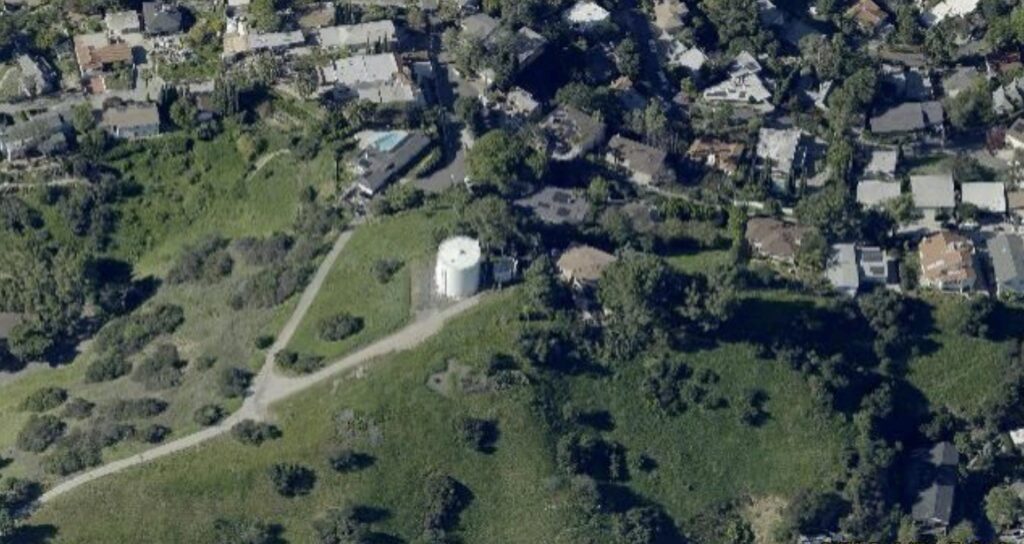 Screenshot 2026-07-08 154958 - Adams Hill Glendale Home For Sale: Private Hilltop Open Space Aerial view of a small white cylindrical silo beside a curved path in a green park bordered by houses and trees.